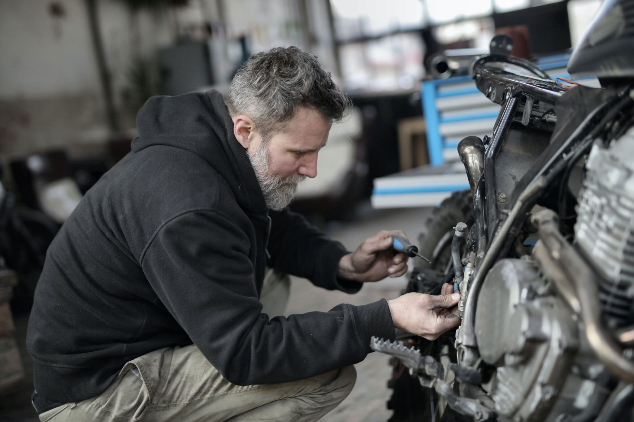 A man is working on a motorcycle in a shop.