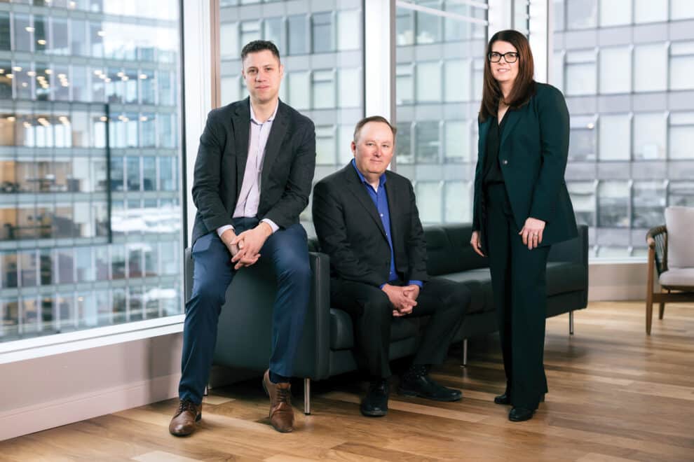 Authors of the article sitting and standing together in an office space.