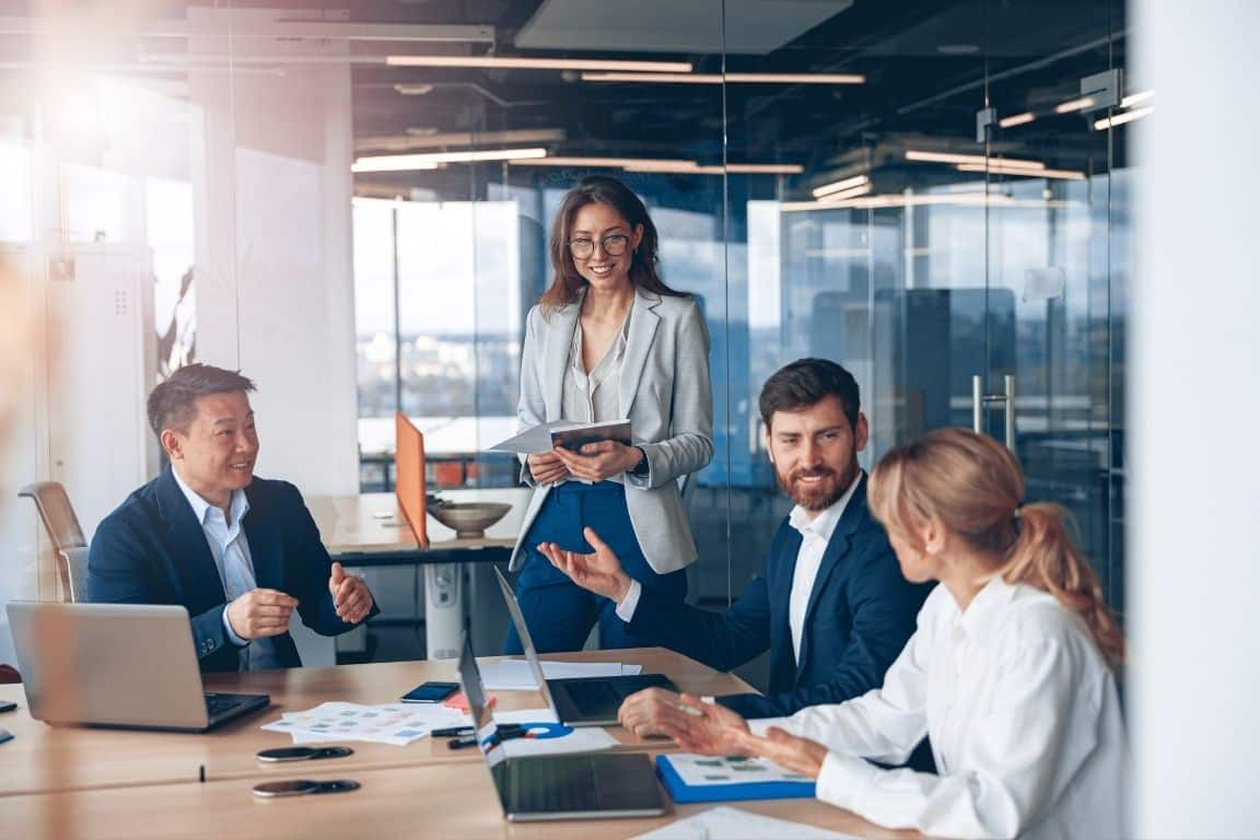 Business team meeting in a modern office, discussing strategy around a conference table.